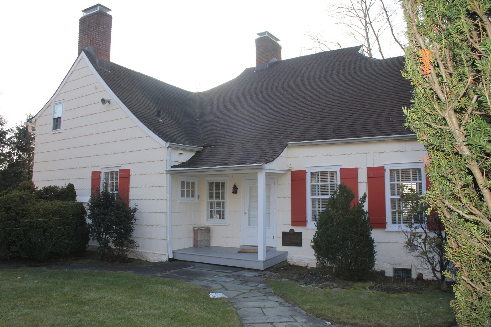 The white-clapboard Cornelius Van Wyck House with red shutters, a pitched roof and two brick chimneys.