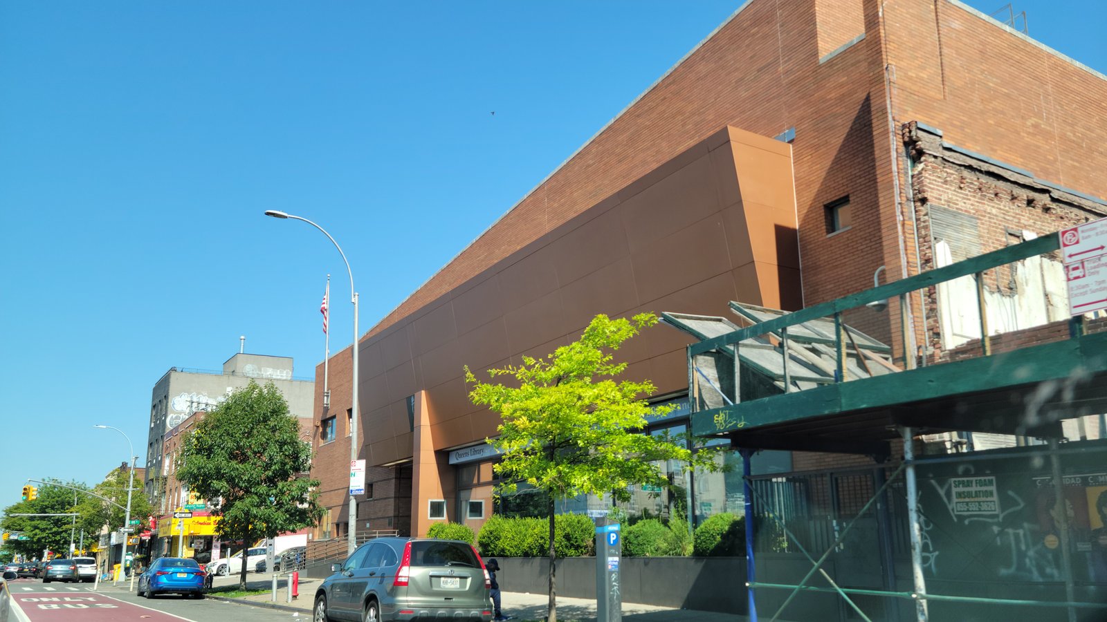 Langston Hughes Library’s brick facade and projecting brown panels beside Northern Boulevard, June 2025.