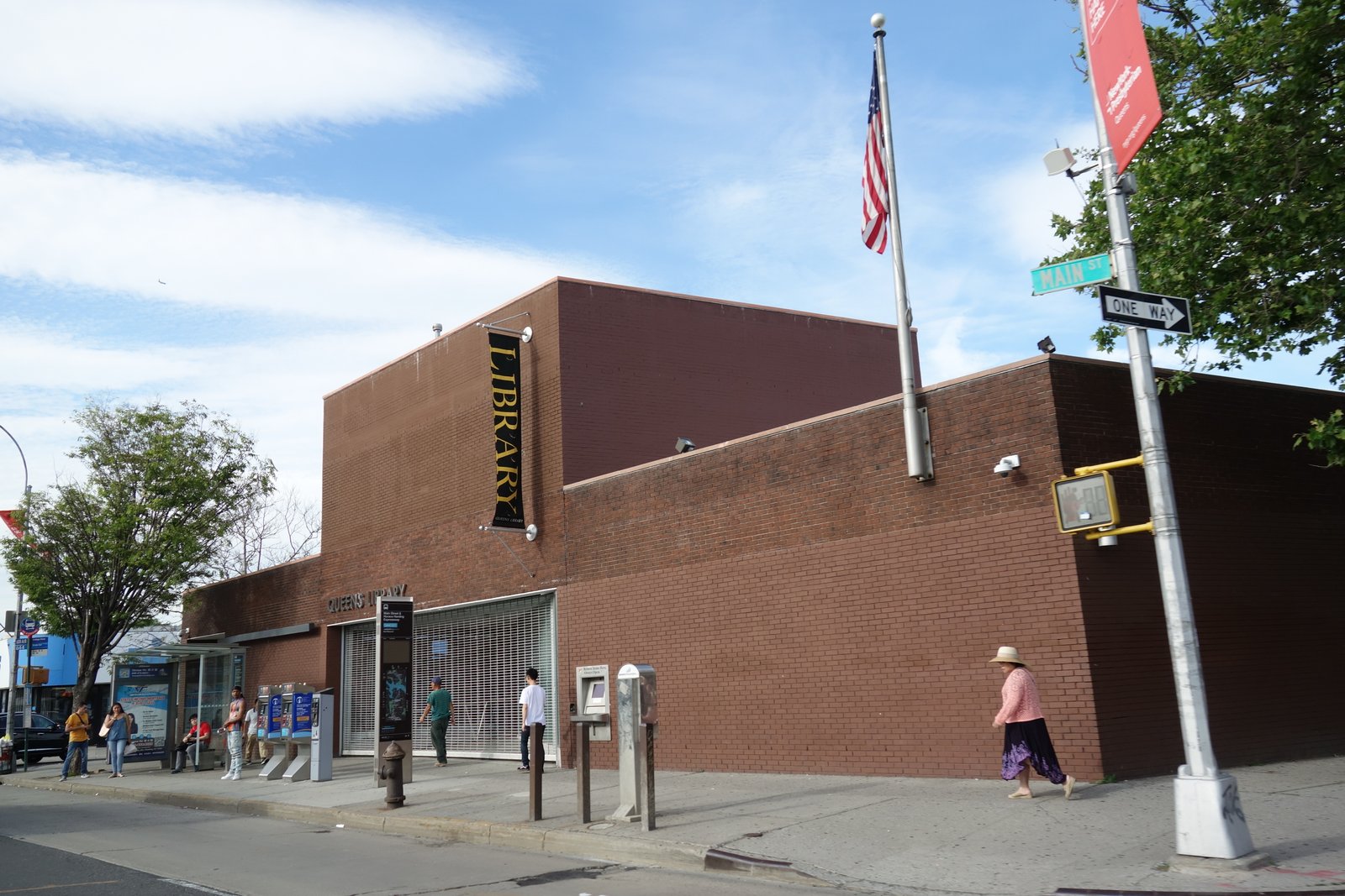 Queensboro Hill Library's red-brick facade, library banner and Main Street sign, June 2018.