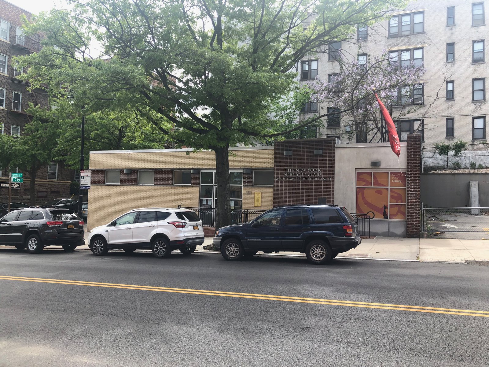 Woodlawn Heights Library on Katonah Avenue, with its branch lettering, entrance and a street tree, photographed in 2020.