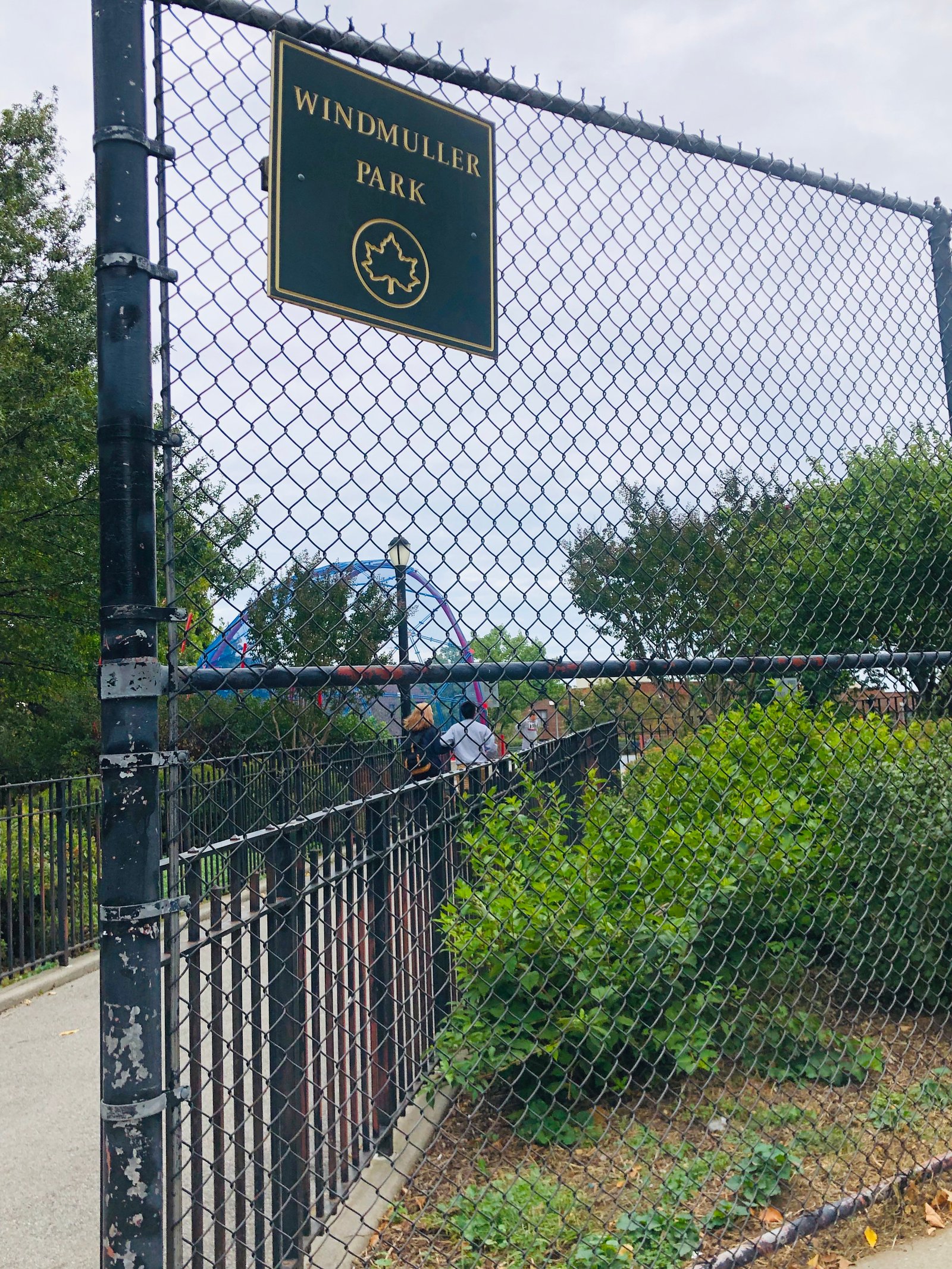 A Windmuller Park sign above the fenced path into the playground.