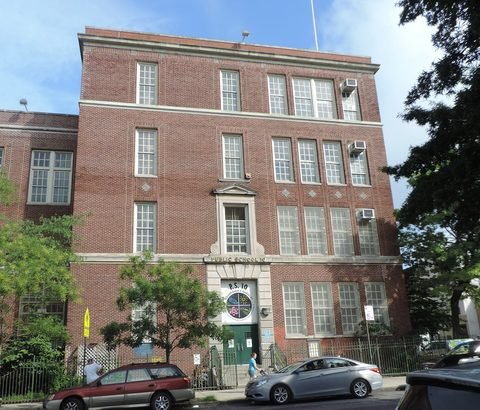A brick school building rises behind trees along Seventh Avenue.
