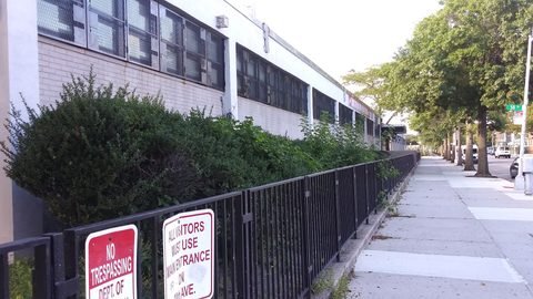 A sidewalk runs beside the high school and its fence.