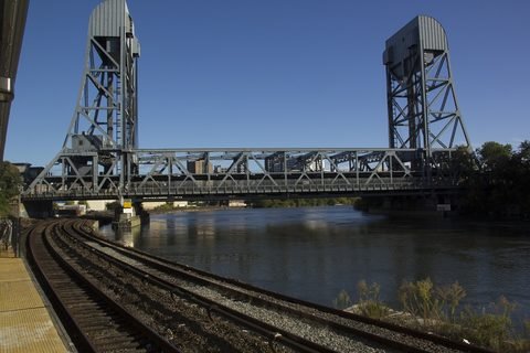 The Broadway Bridge spans the Harlem River beside railroad tracks, seen from Marble Hill station.