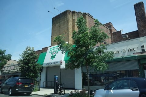 A brick former theater rises above storefronts on Nostrand Avenue.
