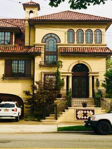 A stucco residence with a tiled roof viewed from the street in Mill Basin.
