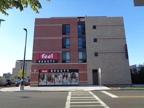 A storefront and apartment building seen across a crosswalk.