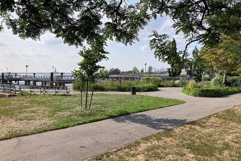 A path and lawn lead toward the waterfront railing at Valentino Park and Pier.