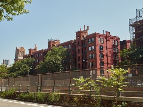 Red brick towers and arcaded facades behind fencing at Cobble Hill Towers.
