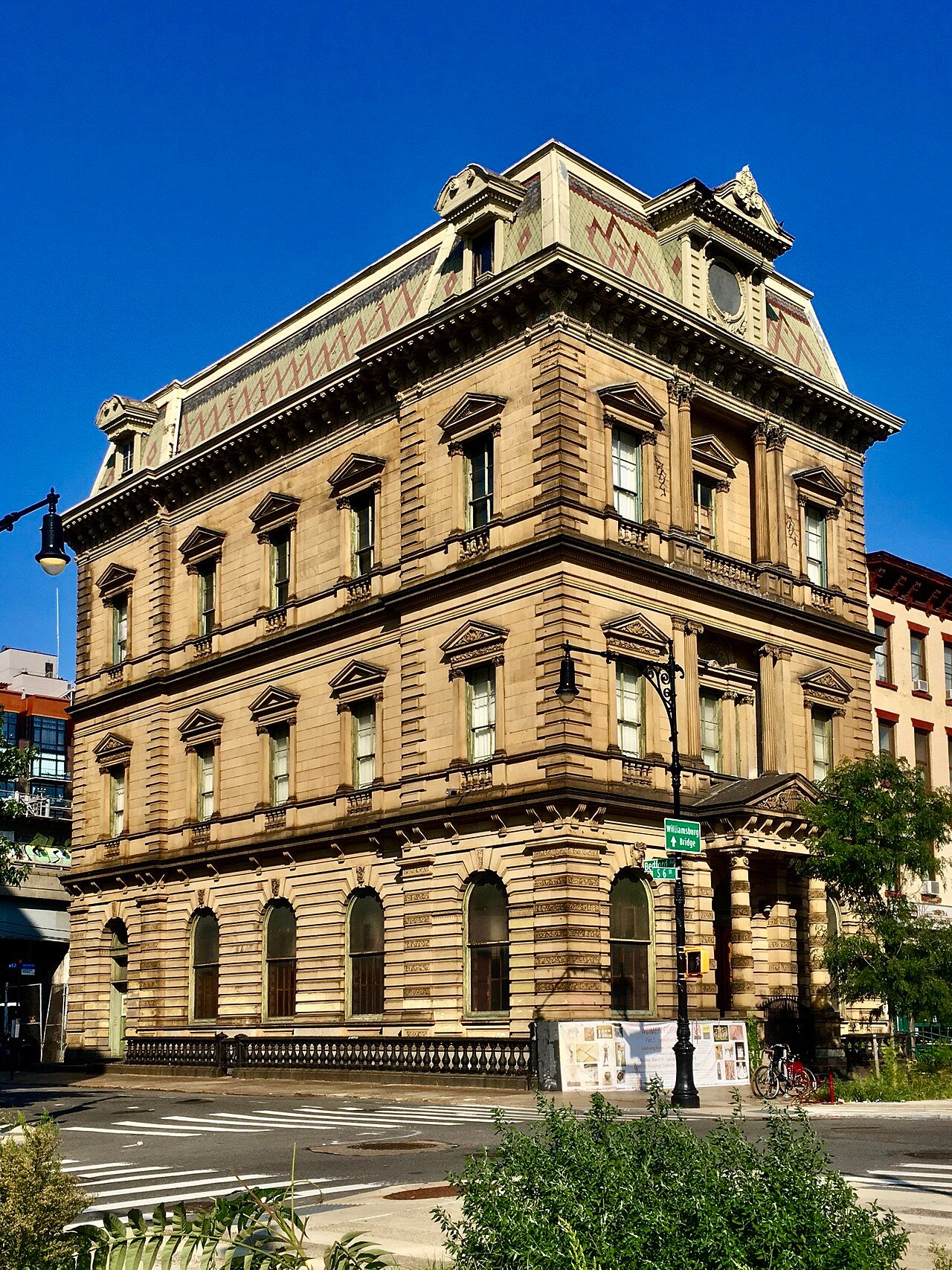 The former Kings County Savings Bank, with carved stone walls, an entrance porch and patterned roof, seen from the Broadway and Bedford Avenue corner in 2020