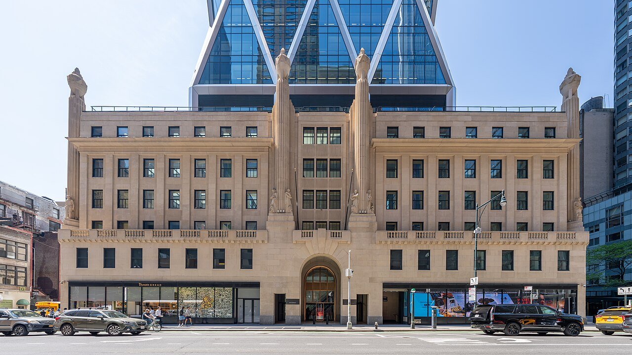 Hearst's historic six-story facade below the later tower's diagonal glass-and-metal framework in 2026