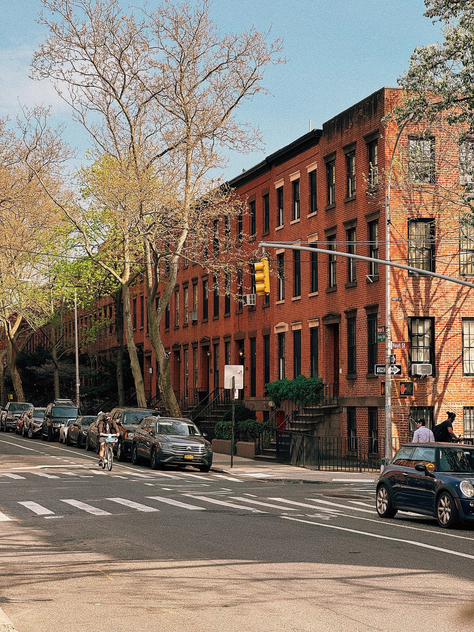 Brick row houses line a Bergen Street corner beneath leafless trees.