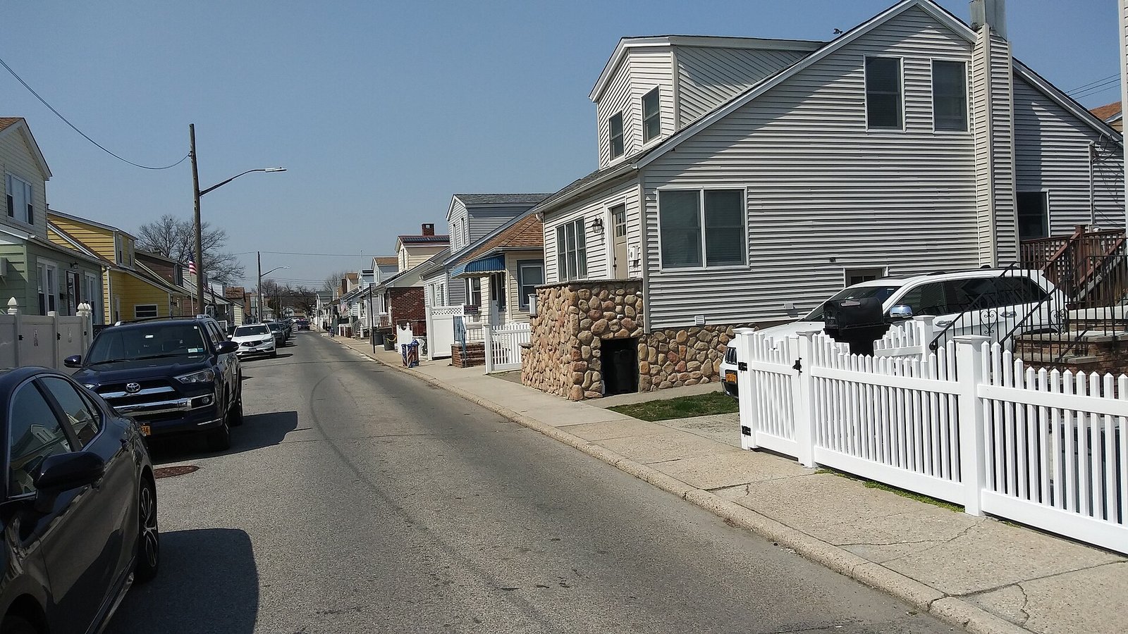 Low houses and parked cars line a residential street.