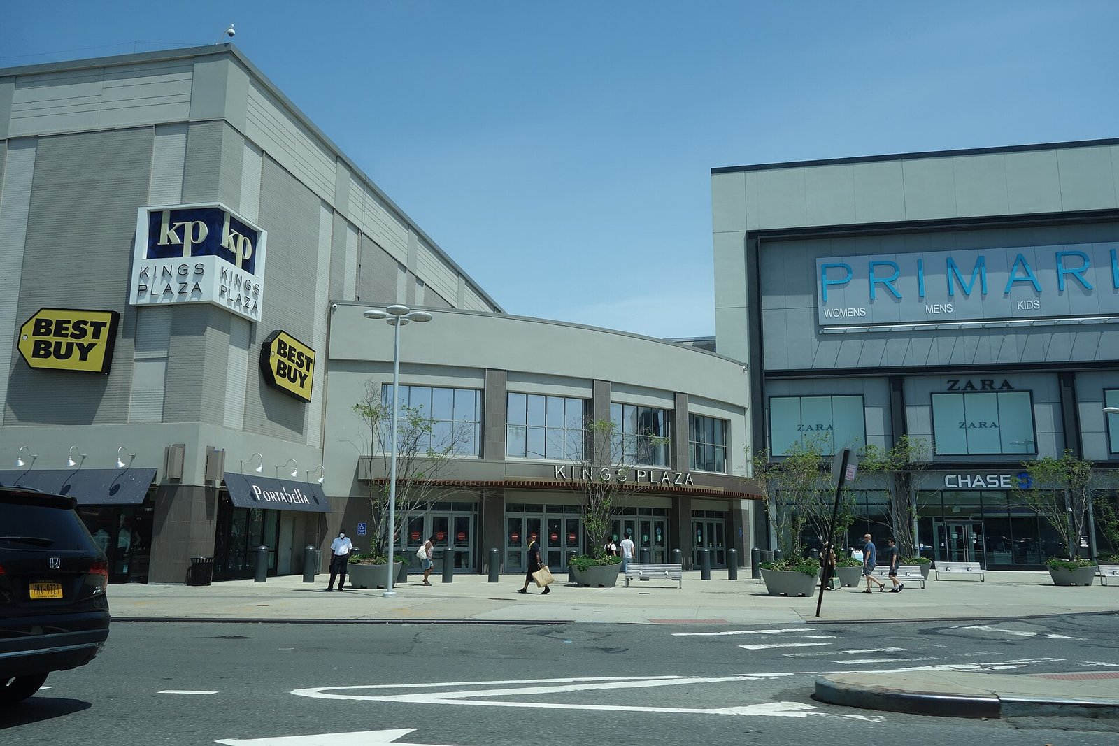 The Kings Plaza entrance and storefronts seen across Flatbush Avenue.