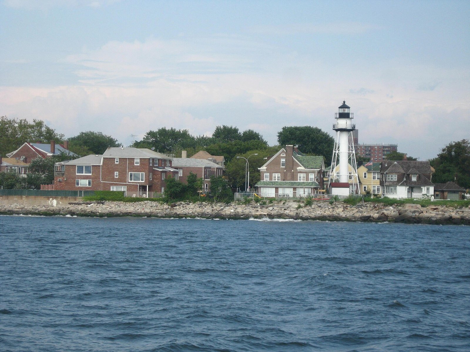 Coney Island Lighthouse rises beside shoreline houses across the water in 2008.