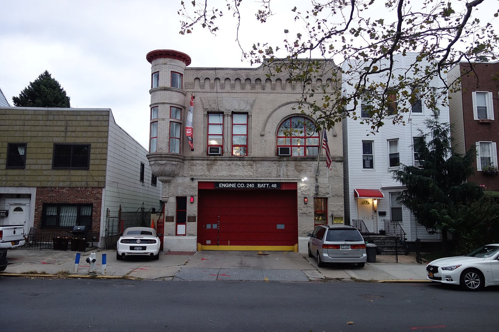 A historic firehouse with a corner turret and red engine door stands on Prospect Avenue.